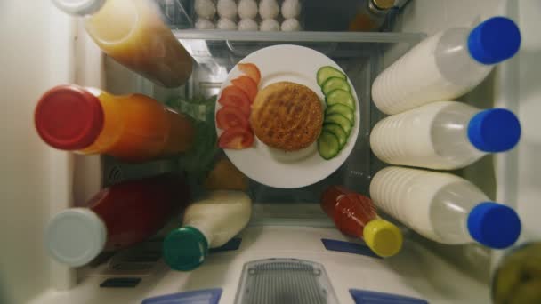 Las manos de los niños toman una hamburguesa del refrigerador. La vista desde el interior de la nevera, el punto superior de disparo — Vídeos de Stock