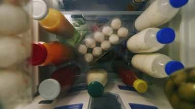 Evde yemek yemek. Kadın da buzdolabından yumurta alır. Çerçevede yalnızca kollarını, görünümden buzdolabının içinde görebilirsiniz