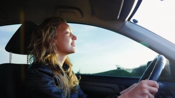 Μια νεαρή γυναίκα οδηγεί ένα αυτοκίνητο κατά μήκος ενός αγροτικού δρόμου, τινάζει το αυτοκίνητο σε μια άνιση άσφαλτο — Αρχείο Βίντεο