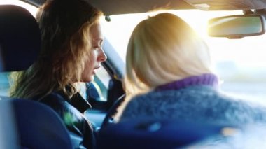 İki kadın arabada iletişim. Gülmek, gülümsemek, tablet keyfini çıkarın. Arkadan görünüş