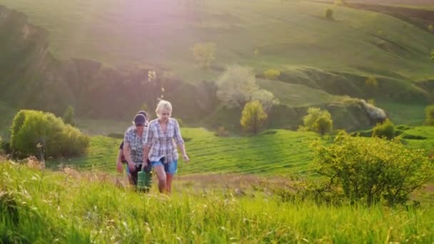 Seit mehreren Generationen kommt die Familie mit Baumsetzling, Schaufel und Gießkanne. in malerischen grünen Hügeln. Das Konzept ist, Bäume zu pflanzen, Freiwilligenarbeit, eine freundliche Familie — Stockvideo