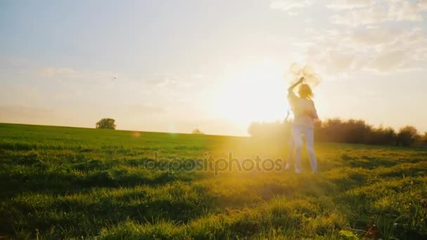 Atividade em qualquer idade. Uma mulher de meia-idade está brincando com sua filha, correndo pelo campo, se divertindo. Conceito - um estilo de vida saudável, uma infância feliz — Vídeo de Stock