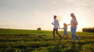 Bir kadın bir düşünceli çocuk - oğlu ve kızı ile pitoresk kırsal yürüyor. Akıllıca giyinmiş, balonlar taşıyorlar. Mavi gökyüzüne karşı günbatımı