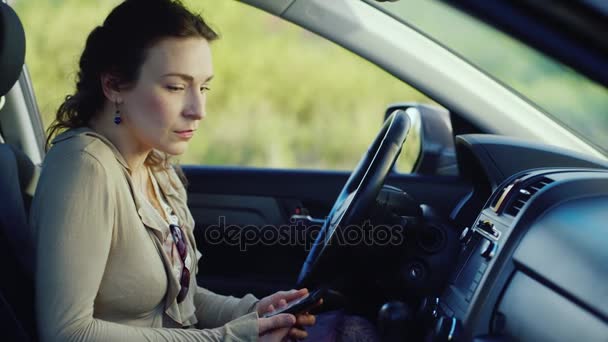 Una mujer frustrada con un teléfono se sienta en el coche. Listo para llorar, muy triste. Concepto - depresión, problemas de las mujeres — Vídeos de Stock