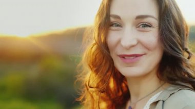 Çekici bir orta yaşlı kadın portresi. O da baktı ve kameraya gülümsüyor. Arkasında ayar güneş güzel saçlarını vurgulamaktadır