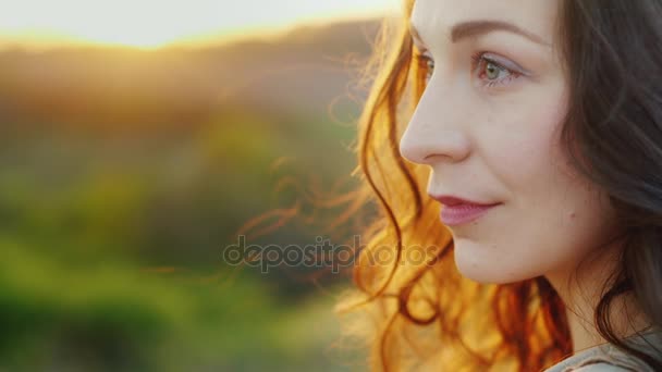 Retrato de perfil de una joven. Sonriendo, mirando a la cámara. Tarde antes del atardecer. Vídeo en cámara lenta — Vídeo de stock