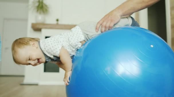 Küçük çocuk evde eğleniyor - baba onunla oynuyor. Bir masaj topu rulo — Stok video