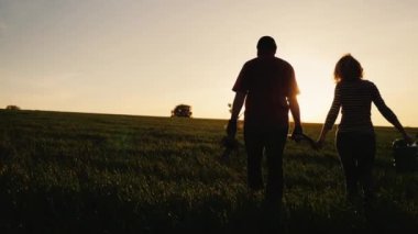 Atış Steadicam: çiftçiler - bir erkek ve bir kadın alanın karşısındaki günbatımında yürüme. Bir ağaç fide, sulama olabilir ve bir kürek taşır. Kavram - Bahçe, gönüllü, yeni bir hayat çalışmalarında