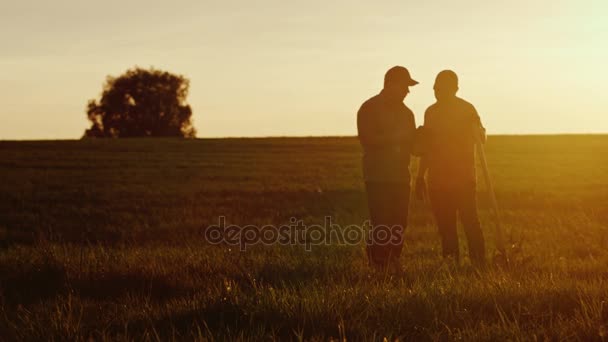 Zwei amerikanische Bauern kommunizieren bei Sonnenuntergang auf dem Feld. Neben ihnen liegt eine Schaufel — Stockvideo