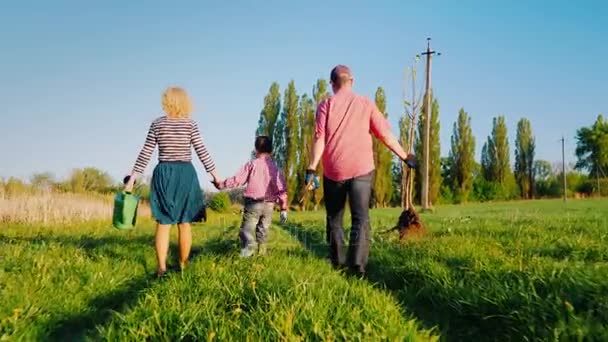 다시 보기: 작은 아들과 함께 농부의 가족이 함께 나무를 심고. 사과 나무 묘 목, 삽 및 급수 패드 곰. Steadicam, 측면 보기 — 비디오