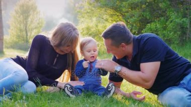 Bir çocuk ile genç bir aile parkta dinleniyor. Senin bebeğin ile 1 yaşında oynamak