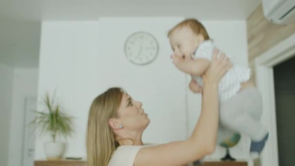 Giovane madre caucasica gioca con il suo giovane figlio in casa. Gettalo sopra la testa, divertiti. — Video Stock
