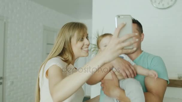 Bir genç çift üst bir selfie bebek oğlu ile birlikte yapar. Yeni parlak evinde. Kavram - yeni eve taşınma partisi, bir çocukla mutlu aile — Stok video