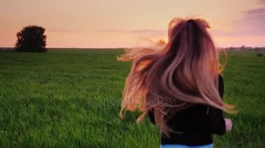 Güzel uzun saçlı genç bir kadın yeşil alan çalışır. Steadicam Slow motion video