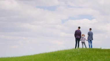Üç çocuk - iki genç ve 6 yaş üstünde yeşil bir tepede duran bir kız. Ufuk dört gözle bekliyorum, hayal. Arkadan Görünüm.
