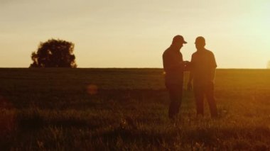 İki çiftçi işçi iletişim alanında bir tablet kullanın. Güzel gün batımı