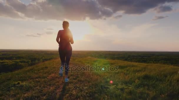 Un bersaglio vicino - una donna corre giù per la collina in un luogo pittoresco. Era stanca, con il pizzo sulla scarpa slacciato. Concetto - movimento in avanti, determinazione, vittoria — Video Stock