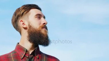 Sakallı genç bir adam portresi. Mavi gökyüzü karşı dört gözle mutlu