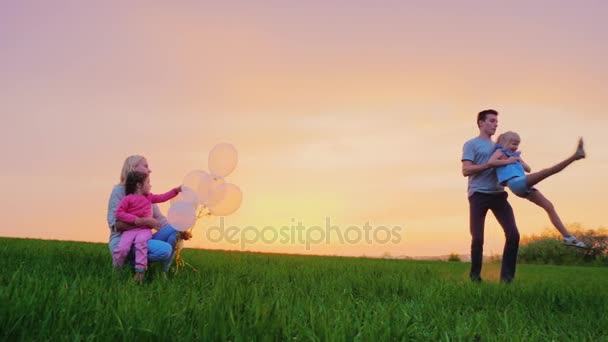 Mutter und Kinder spielen draußen. der ältere Bruder kreist um seine jüngere Schwester, die Familie hat Spaß — Stockvideo
