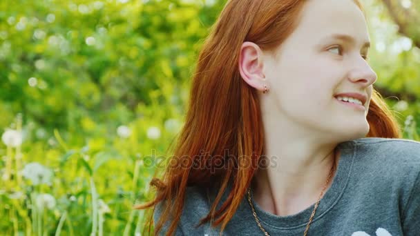 Portrait d'une jolie adolescente rousse. Elle sourit et rêve. Le soleil illumine magnifiquement ses cheveux. Vidéo au ralenti 4K — Video