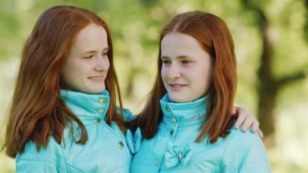 Porträtt av tonårs systrar tvillingar. Två rödhåriga flickor ler, tittar på kameran — Stockvideo