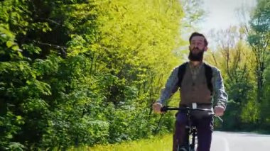 Steadicam atış eğimli: sakallı bir adam bir bisiklet ile gidiyor. Kamera tekerlekli bisikletçi için taşınır