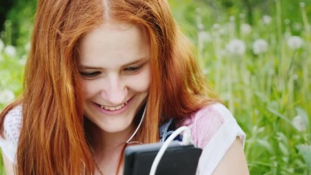 Усміхнена дівчинка-підліток насолоджується телефоном. Відпочиває на природі - завжди на зв'язку — стокове відео
