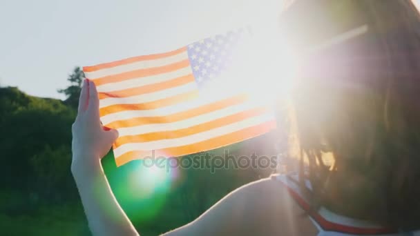 Dos gemelas con una bandera americana sobre un fondo azul. Vista trasera. Día de la independencia — Vídeo de stock