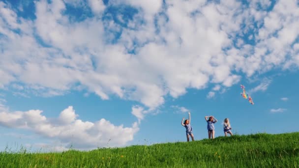 Trois sœurs jouent avec un cerf-volant sur une colline verdoyante. Composition du copyspace — Video