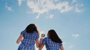 İki kadın Kazananlar Şampiyonlar Kupası ile. Gökyüzüne ellerini yukarı kaldır, zafer sevinirler. Arkadan Görünüm