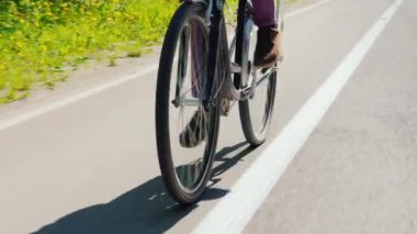 Hippi erkek bir Bisiklete binmek sahiptir. Açık bahar günü. Steadicam atış