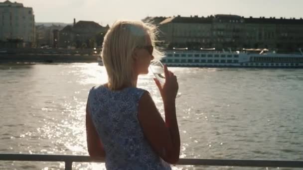 Uma mulher com uma taça de champanhe navega no barco. Cruzeiro no Danúbio, contra o fundo da costa de Budapeste — Vídeo de Stock