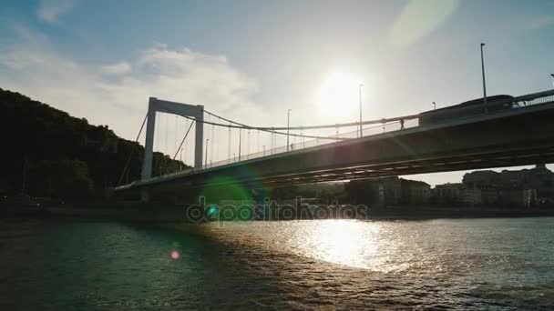 Nade sob a ponte em Budapeste ao pôr-do-sol. Cruzeiro no rio, vista do barco turístico flutuante — Vídeo de Stock