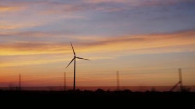 Bir rüzgar jeneratörü ile kırsal üzerinde gün batımı. Bir seyahat araba penceresinden görüntülemek