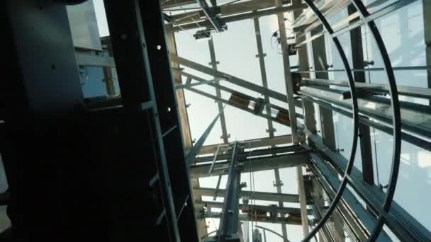 De lift gaat naar beneden in de schacht. Bovenaan ziet u het mechanisme van de lift, de kabels en de blauwe hemel — Stockvideo