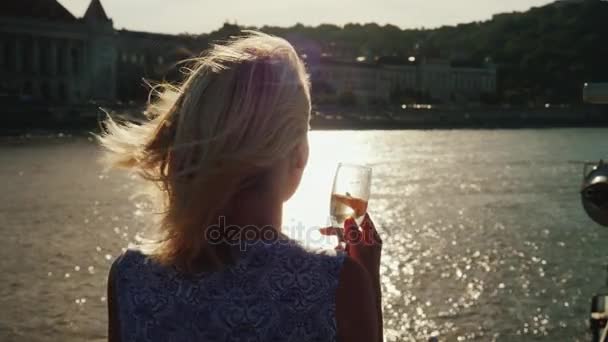 Njut av flodkryssningar på Donau. En kvinna med ett glas i handen ser ut vid strandlinjen i Budapest — Stockvideo