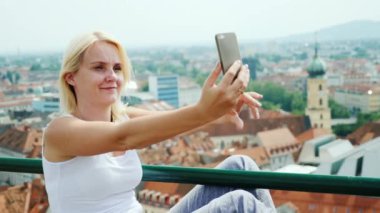 Bir genç kadın fotoğrafları kendini Graz Avusturya cityscape karşı. Euro-gezi