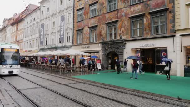 Graz, Oostenrijk, juni 2017: Verkeer van trams en voetgangers op Herrengasse street in regenachtig weer. De stad van Graz in Oostenrijk — Stockvideo