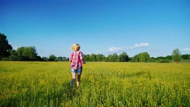 Steadicam toma de cámara lenta: Mujer despreocupada corre a través de un prado floreciente . — Vídeo de stock