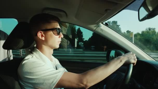 Un joven con gafas de sol conduce un coche. — Vídeos de Stock