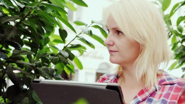 Porträtt av en ung kvinna som njuter av en tablett i en street café — Stockvideo