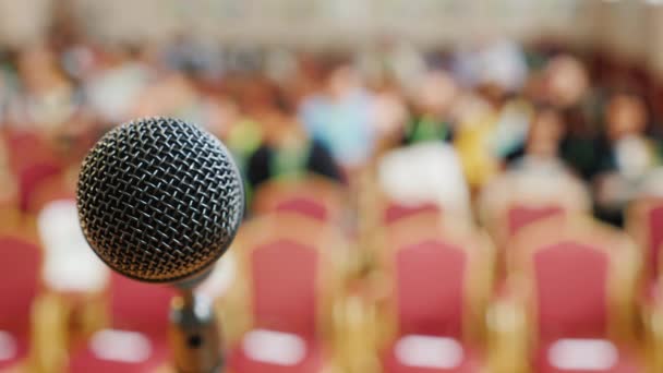 Estante con un micrófono y una audiencia en el fondo. Concepto - conferencia de prensa — Vídeos de Stock