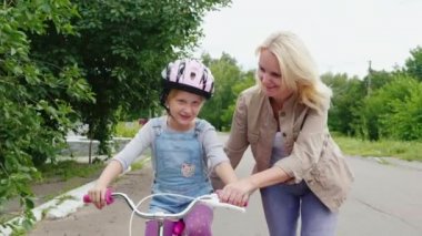 Anne bir Bisiklete binmek için bir kızı öğrenir. O kız ilk başarı sevinir. Steadicam atış