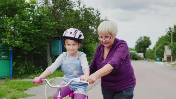 Babcia uczy jej wnuczka, jak jeździć na rowerze. Pierwsze sukcesy dzieci, aktywności w starszym wieku — Wideo stockowe