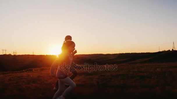 Mamá y su hija corren al atardecer. Tiempo feliz con los niños, estilo de vida activo — Vídeos de Stock