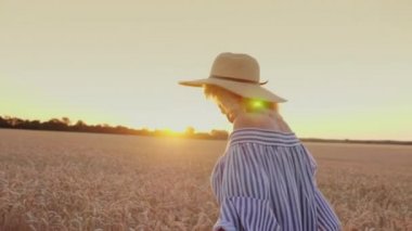 Arka görünümü: şapkalı bir genç bir kadın buğday alan bir gezinti keyif alıyor, mutlu bir şekilde ileri, gülümser gider.
