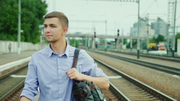 Успешный молодой человек идет по железнодорожному вокзалу Перрон. Прибытие в командировку, путешествия — стоковое видео