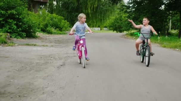 Dwa gospodarstwa dzieci jadą rowery na wsi. Steadicam strzał — Wideo stockowe