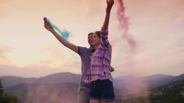 Jeune couple jouant avec des chips de fumée. Fumée amusante et colorée autour d'eux — Video