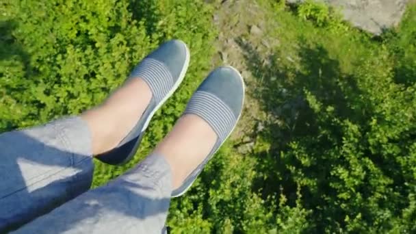 Kadın ayakları ormanıyla kaplı uçurumun üzerinden uçuyor. Teleferik, çerçeve üzerinde gidiş sadece ayakkabılar bacaklar görebilirsiniz — Stok video